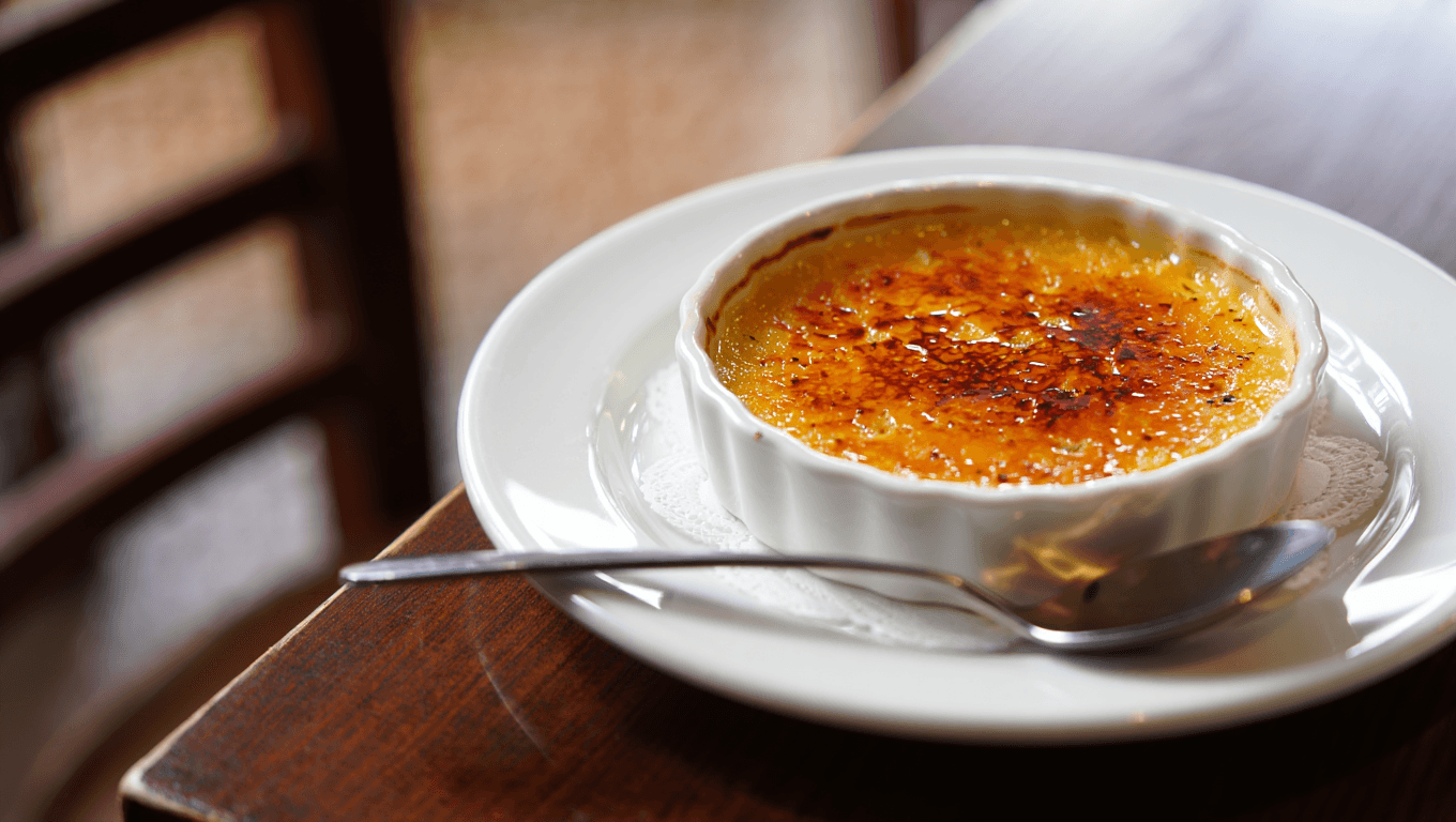 Classic French crème brûlée with a torched caramelized sugar top in a white ramekin